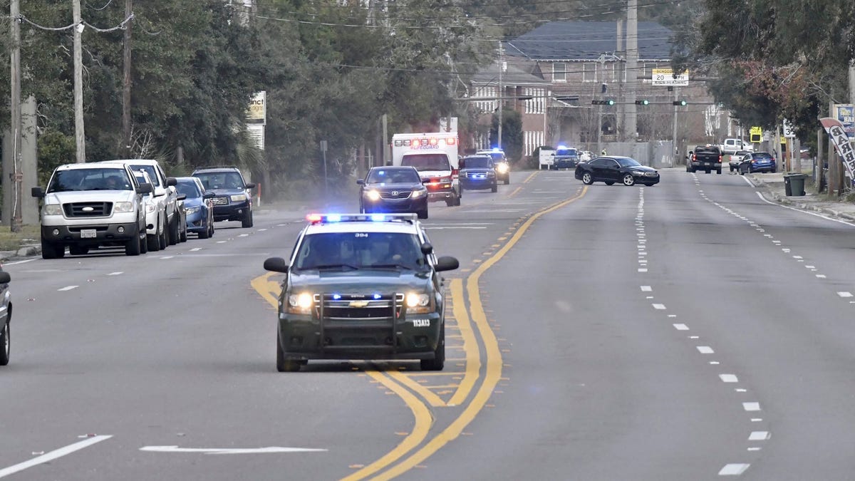 Police cars escort an ambulance after a shooter opened fire inside the Pensacola Air Base in Florida on Friday, Dec. 6, 2019.
