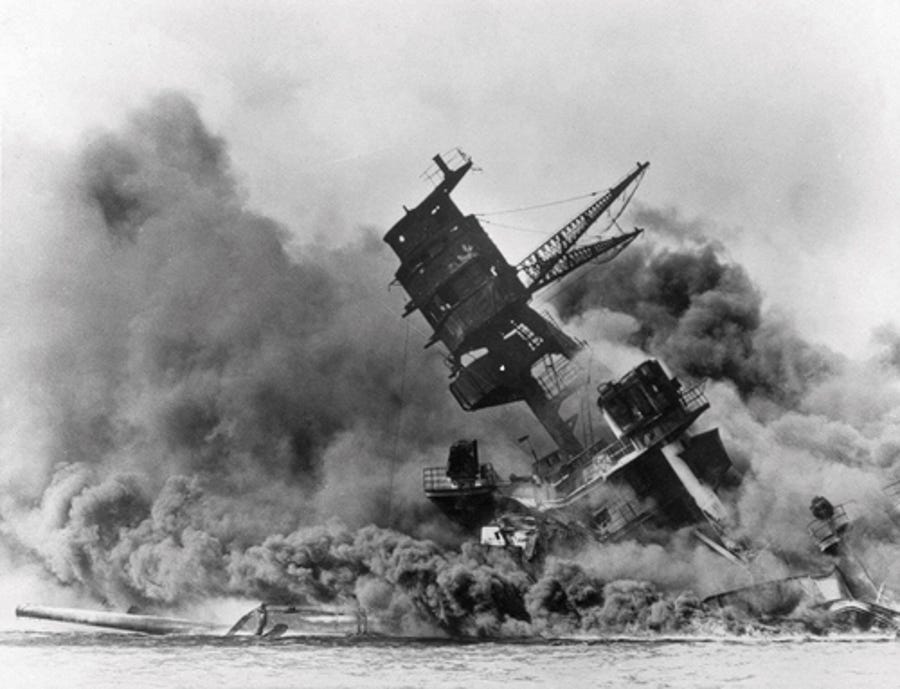 In this Dec. 7, 1941, photo, smoke rises from the battleship USS Arizona as it sinks during the Japanese attack on Pearl Harbor, Hawaii. Divers will place the ashes of Lauren Bruner, a survivor from the USS Arizona in Pearl Harbor, in the wreckage of his ship during a ceremony this weekend.  Bruner died earlier in 2019 at the age of 98.