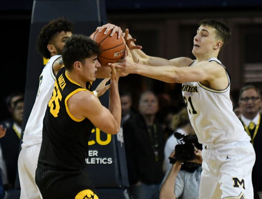 Michigan guard Franz Wagner (21) and forward Isaiah Livers, rear, battle Iowa center Luka Garza (55) for a rebound in the second half.