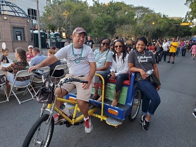 Mike Goldstein, now the owner of Capital City Pedicabs, and some riders pose on a pedicab while at a Tallahassee event.