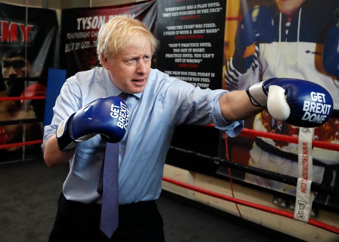 In this Tuesday, Nov. 19, 2019 file photo Britain's Prime Minister Boris Johnson poses for a photo wearing boxing gloves during a stop in his General Election Campaign trail at Jimmy Egan's Boxing Academy in Manchester, England.