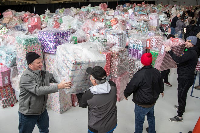 From left, volunteers from Ford Motor Company's John Rohlf, Tony Kabacinski and Tim Scott, help load gifts onto a truck during the Operation Good Cheer at the Oakland County Airport in Waterford, Friday, Dec. 6, 2019.