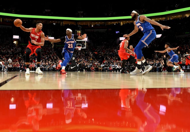 Portland Trail Blazers guard CJ McCollum, left, dribbles the ball on New York Knicks guard Damyean Dotson, center, as center Mitchell Robinson, right, closes in during the second half of an NBA basketball game in Portland, Ore., Tuesday, Dec. 10, 2019. The Blazers won 115-87.