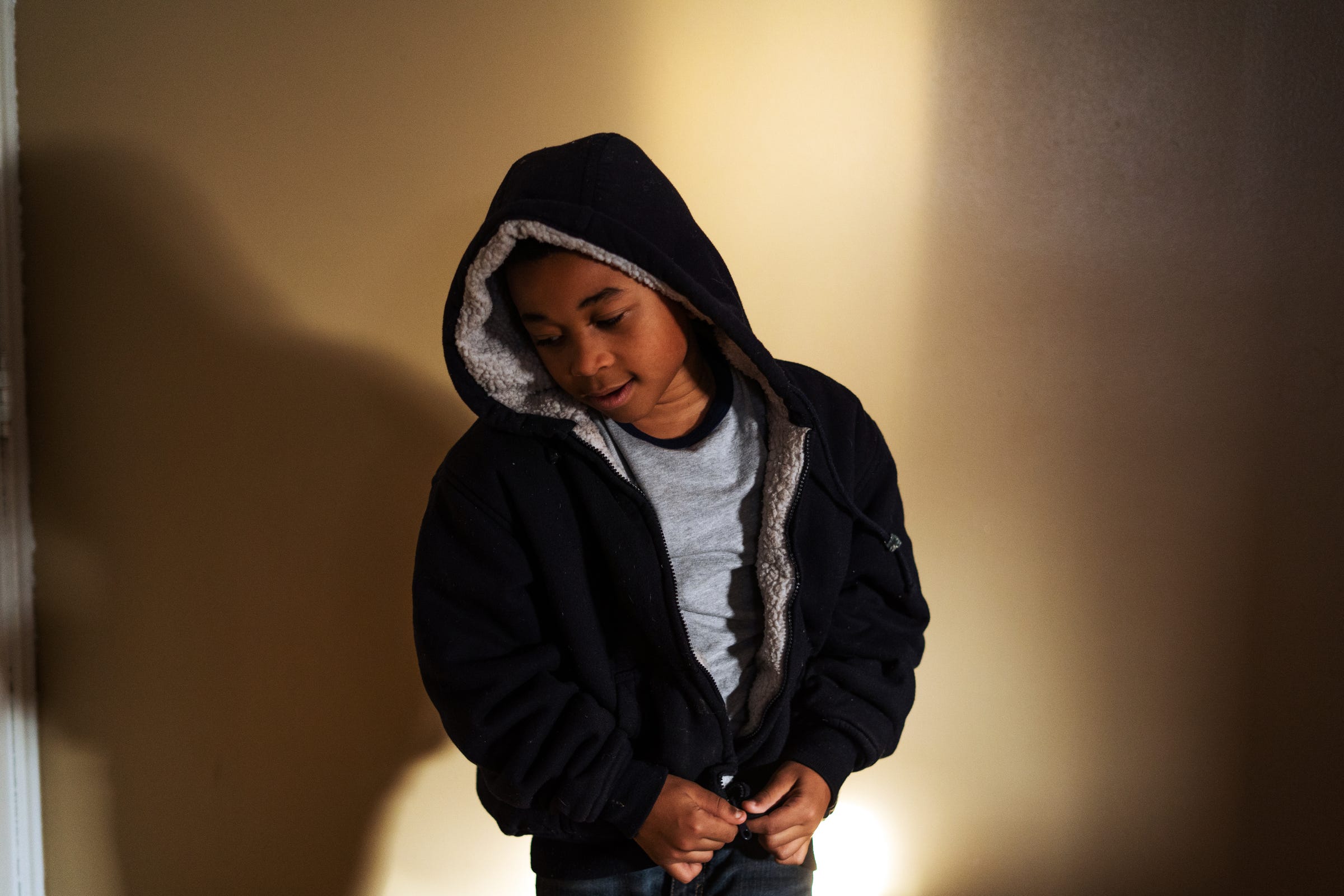 Jaylon Tyson, 11, of Flint zips his hoodie before going outside of his home on Flint's north side on Wednesday, December 11, 2019.