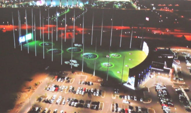 Une représentation du site Topgolf sur Outlet Drive montre le practice éclairé pendant les heures du soir;  le bâtiment principal à droite abritera des restaurants, des bars et des aires de jeux.