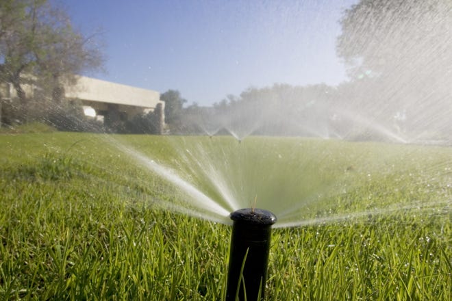 Sprinklers water winter rye grass in the backyard of a Paradise Valley home.