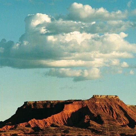 A group of clouds forms above the red mesas of Maj