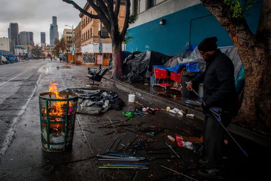 A homeless man made a fire from trash to keep warm on Thanksgiving Day in Los Angeles. The Supreme Court has been asked to let cities criminalize homelessness.