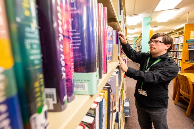 Library branch assistant Thomas Mihalich organizes books on a shelf Friday, Nov. 13, 2019, in St. Clair County Library's main branch in Port Huron.
