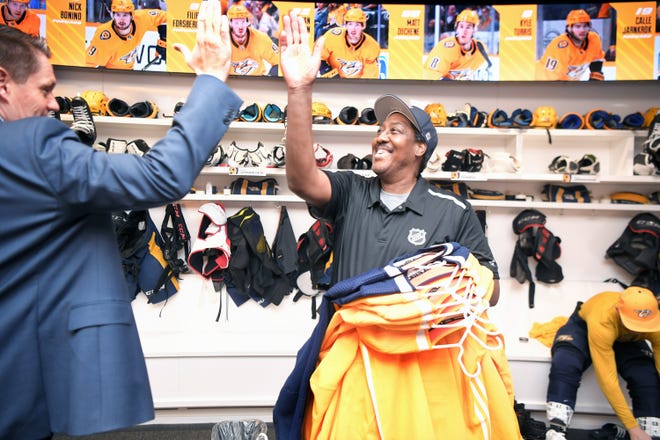 Predators clubhouse assistant Craig Baugh high-fives Brandon Walker, Predators Manager of Hockey Operations,  in the team locker room at Bridgestone Arena on Tuesday, Dec. 10, 2019.  Baugh has been with the Predators as a clubhouse assistant since they began the franchise.