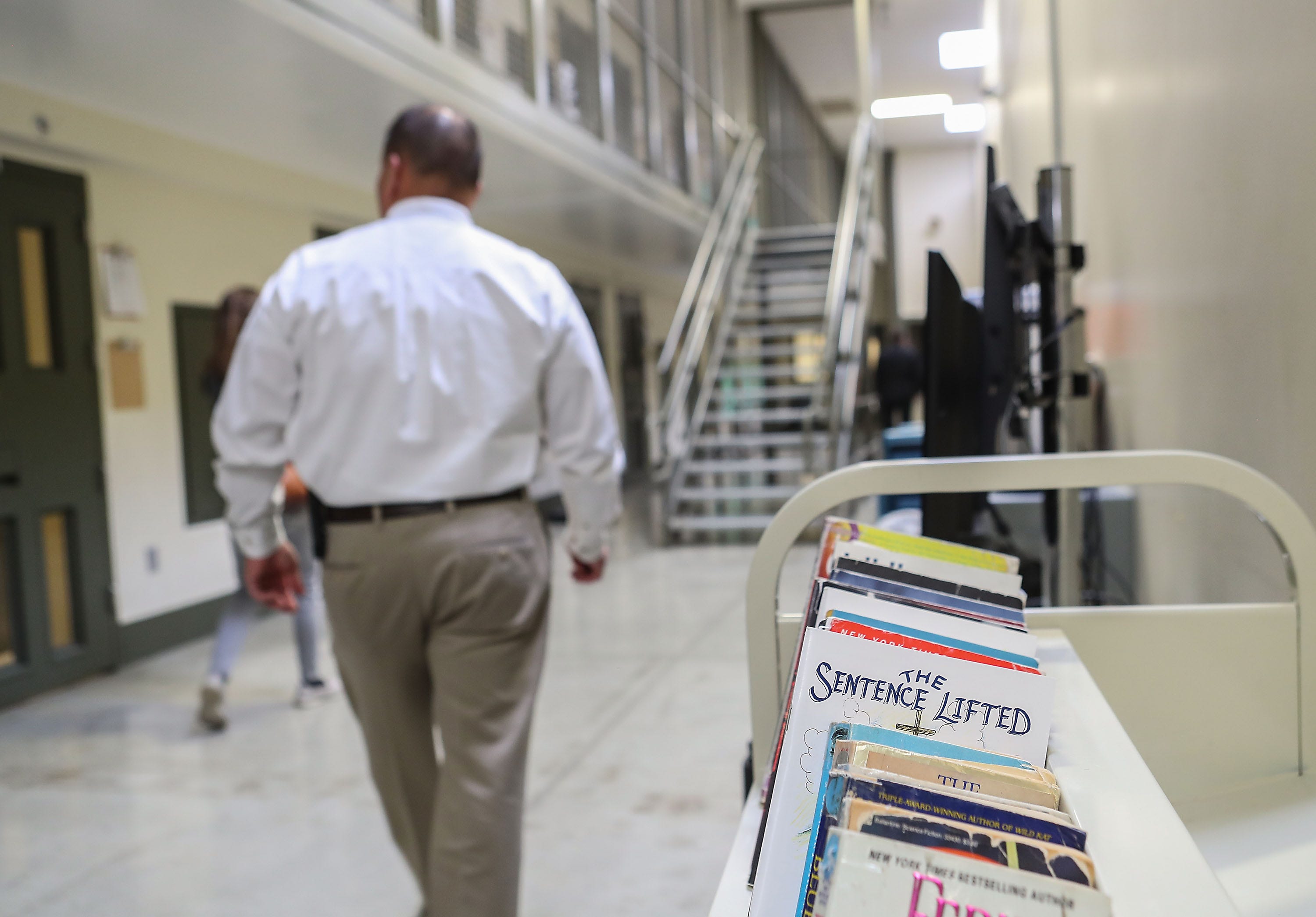 An ICE officer walks by a cart of books meant for detainees in the segregation unit at the U.S. Immigration and Customs Enforcement's (ICE) Adelanto processing Center in Adelanto, California.