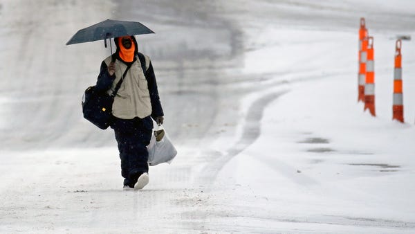 A man walks down a snowy street, Monday, Dec. 16, 