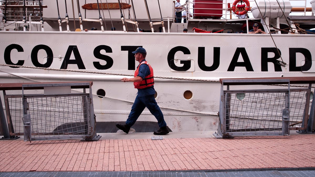 A member of the U.S. Coast Guard walks past the U.S. Coast Guard Cutter Eagle as it docks along the Hudson River next to the Intrepid Air and Space Museum, August 4, 2016 in New York City. Thursday is National U.S. Coast Guard Day in the United States.