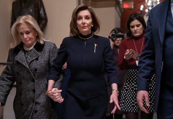 Speaker of the House Nancy Pelosi, D-CA, holds hands with Rep. Debbie Dingell, D-MI, on Dec. 18, 2019, as they walk to the chamber where the Democratic-controlled House debated impeachment charges against President Donald Trump.