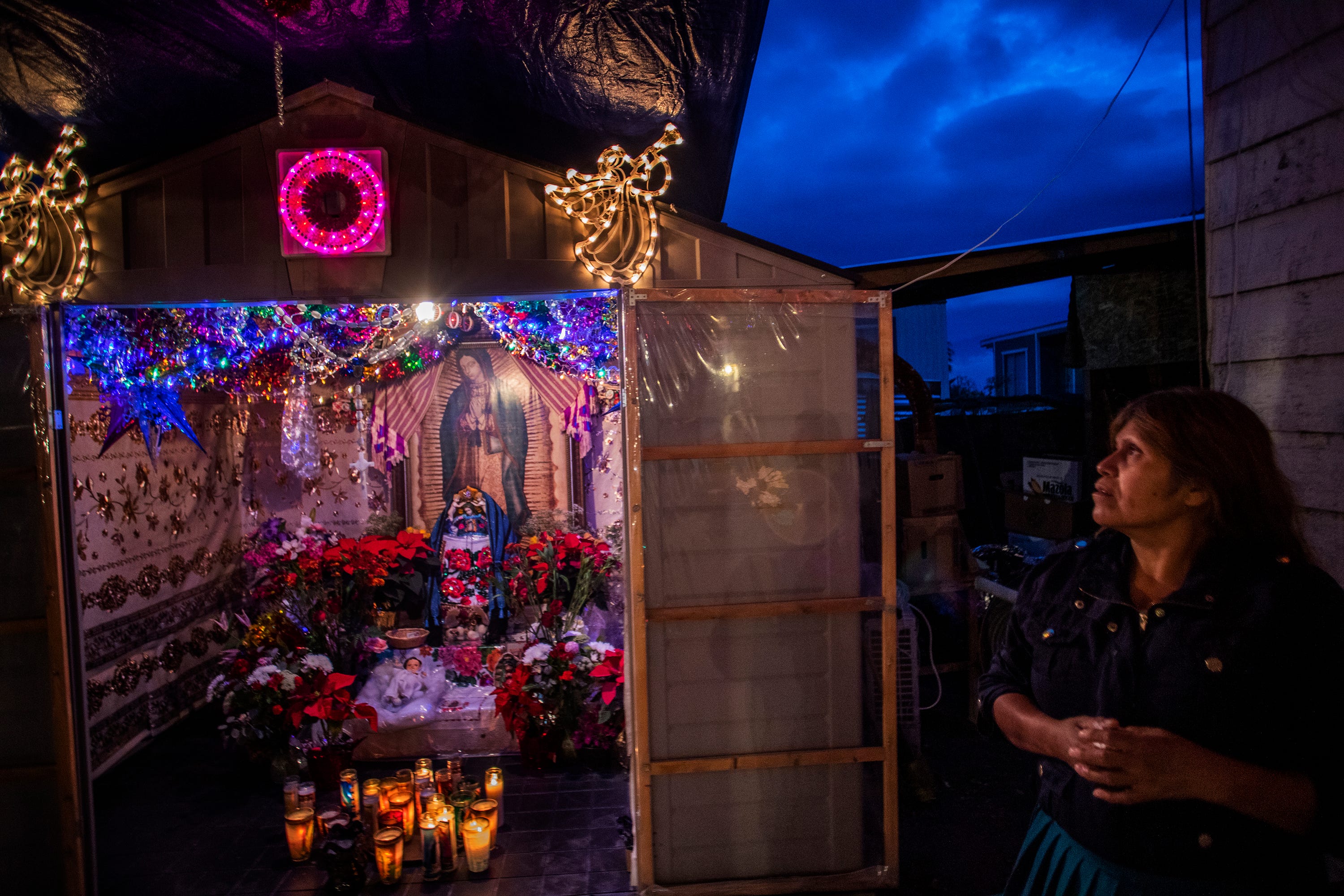 Maria Elias takes a moment to say a prayer to the Virgin of Guadalupe. The altar has been at her home for a year after she and her husband were selected as godparents by her Purépecha community, an honor bestowed every year on one of the families of the Purepecha in the Coachella Valley.