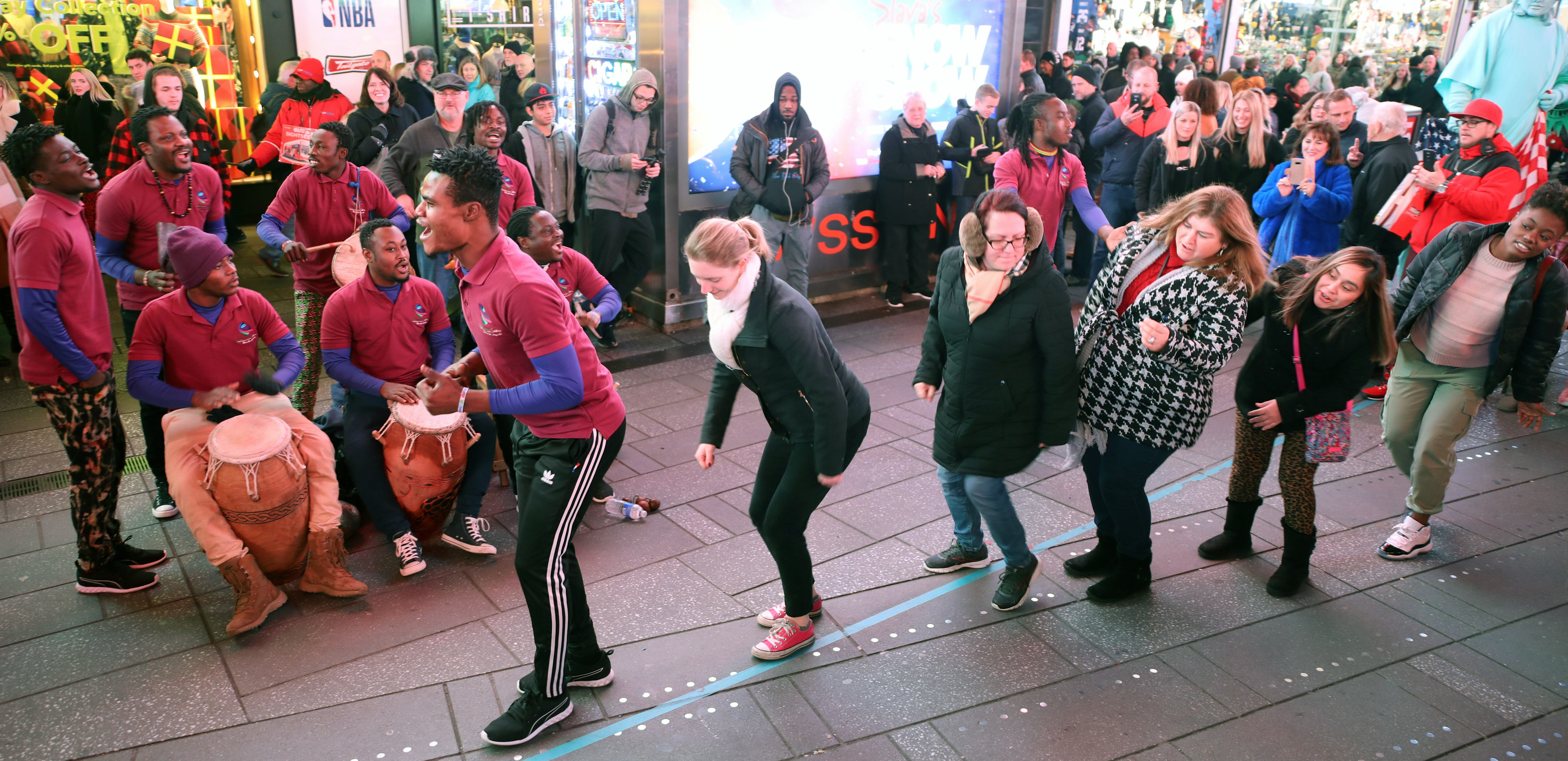 People from the crowd join Nii Tetteh Quarshie of Womba Africa, followed by Kate Huggler-Rubin, in a dance as the group busks in Times Square.