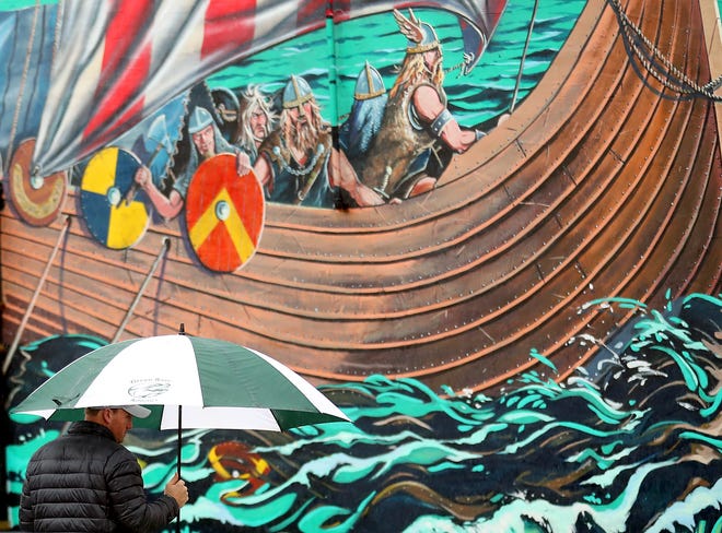 The viking mural looms in the background as an umbrella toting pedestrian crosses the street in downtown Poulsbo on Friday.