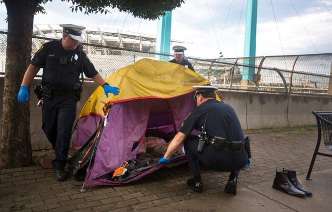 Cincinnati police officers check an abandoned tent in August 2018 along Downtown's Third Street. The search came after Judge Robert Ruehlman banned the homeless from camping.