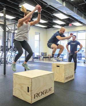 Jason Kelly watches as Chris Smith and Callie Kelly demonstrate the exercises at Lyndon's Distilled Fitness.  19 December 2019