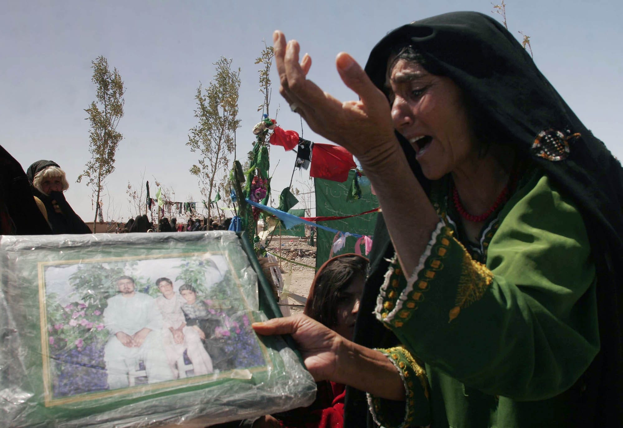 An Afghan woman mourns during a ceremony in Azizabad. She is holding a poster with photos of her family member killed in the August 22 raid.