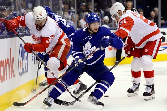 Detroit Red Wings defenseman Brian Lashoff (32) and teammate Valtteri Filppula (51) vie for control of the puck with Maple Leafs left wing Zach Hyman.