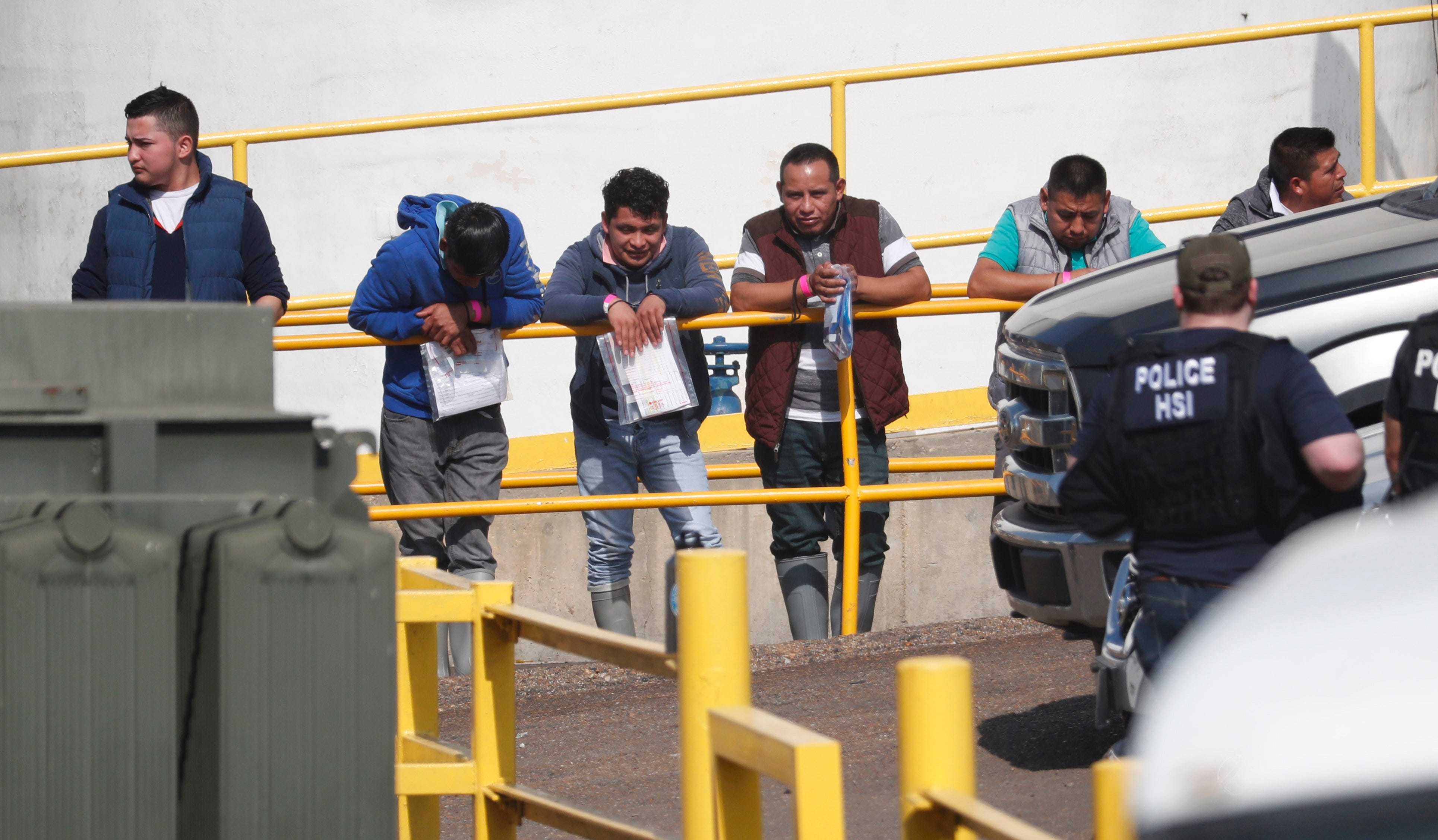 In this Aug. 7, 2019 file photo, handcuffed workers await transportation to a processing center following a raid by U.S. immigration officials at seven Mississippi food processing plants, including this Koch Foods Inc., plant in Morton, Miss. Federal agents arrested 680 mostly Latino workers in the largest workplace sting in the U.S. in at least a decade. The early morning raids were part of a large-scale operation targeting owners as well as undocumented employees. These raids are considered one of the state's top stories for the year.