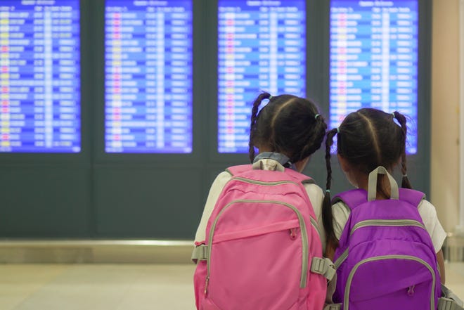 Children checking their flight at information board in international airport terminal. (Dreamstime/TNS)