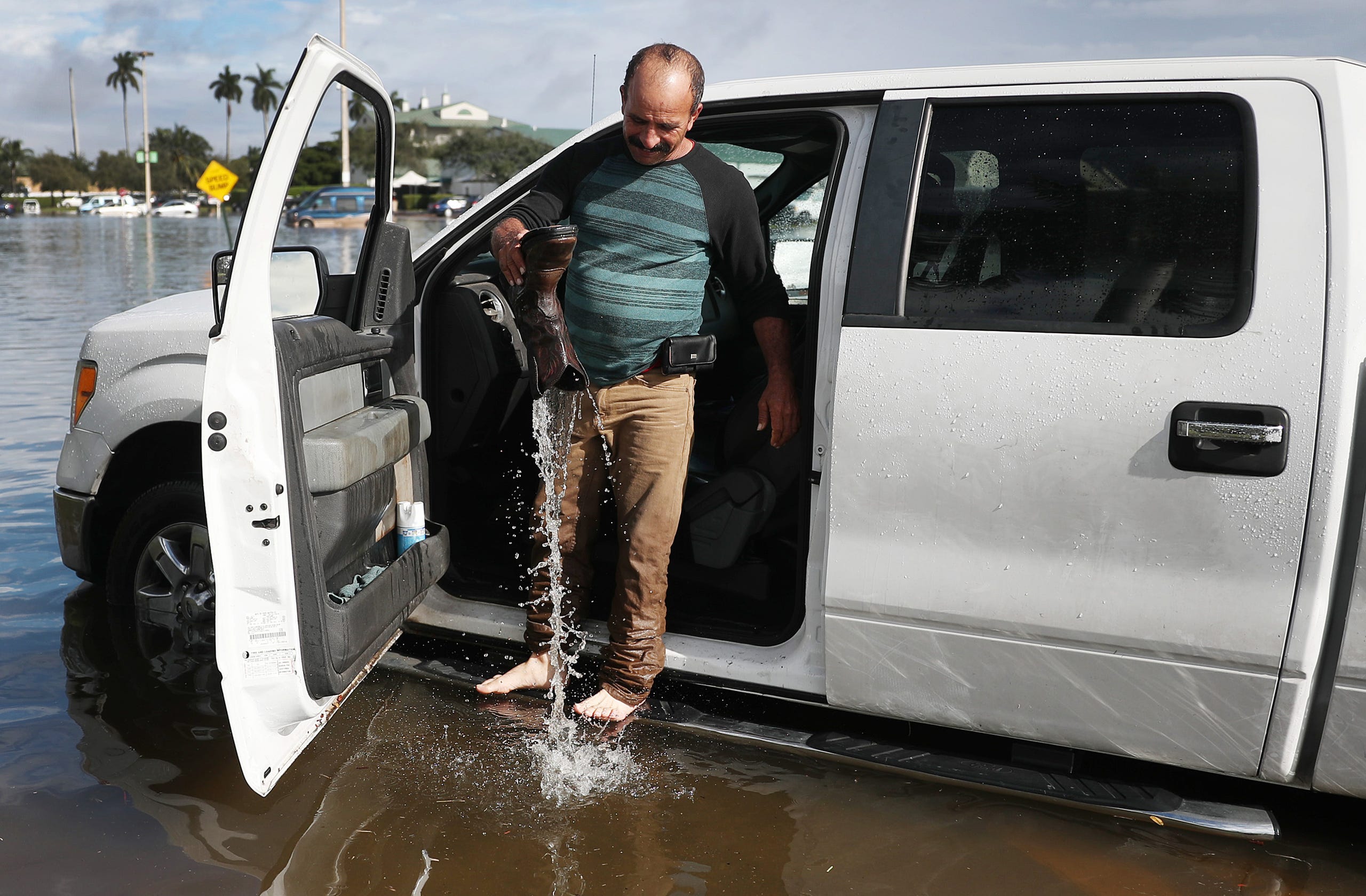 Julio Borges empties his boot of water as he tries get his truck to start after it was inundated with flood waters on Dec. 23, 2019 in Hallandale, Fla. 