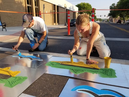 Abigail Lichliter and Clark Carlson-Thompson, Get Fit Great Falls volunteers, paint crosswalks downtown. The effort aims to make downtown more friendly and walkable.