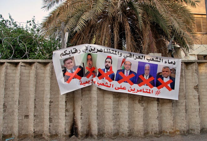 A poster with defaced pictures of Iraqi politicians and Arabic that reads, "the blood of the protesters and the Iraqi people is on your necks, the conspirators on the people and the religious authority," in hung on the wall near Tahrir Square during anti-government demonstrations in Baghdad, Iraq, Thursday, Dec. 26, 2019.