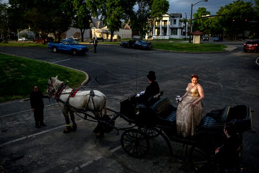 Castle High School student Rachel Landrum, center right, gets back on a Horseshoe Bend Carriage Co. carriage after making a pit stop to take prom pictures by the river with her boyfriend Conner Gorman, not pictured, and CHS student photographer Randy Cox, bottom right, in downtown Evansville, Ind., Saturday, April 27, 2019. Randy, center left, and Sheila O'Risky, far left, lead the couple and photographer through downtown Evansville before taking them to their prom at Old National Events Plaza.