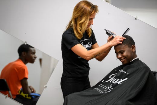 Izaeias Smith, 14, watches his brother Demetrius Smith, 12, get a free haircut from Hailee Burkett at Jerald's Barbershop in Evansville, Ind., Monday morning, Aug. 5, 2019. The barbershop partnered with 9 Fruits Beauty Salon, located in the same building, and the youth mentoring group Young and Established to give kids free haircuts before going back to school this week. 
