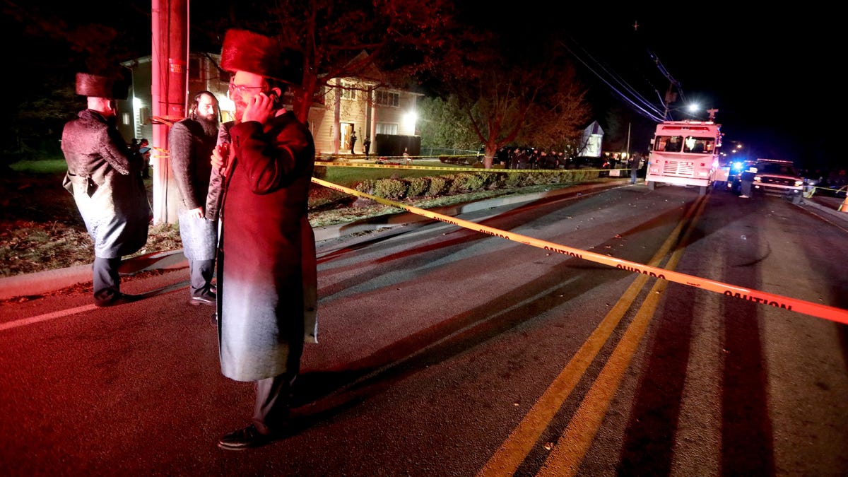 Hasidic Jewish men stand outside the home of a rabbi on Forshay Rd. in Monsey, N.Y. Sunday night after a man entered the house and stabbed multiple people who were there for a Hanukkah gathering. 