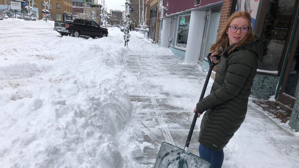 Volunteers help a woman dig out her parked car on 