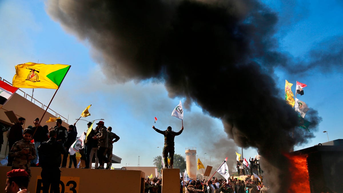 Protesters burn property in front of the U.S. embassy compound, in Baghdad, Iraq on Dec. 31, 2019. Dozens of angry Iraqi Shiite militia supporters broke into the U.S. Embassy compound in Baghdad on Tuesday after smashing a main door and setting fire to a reception area, prompting tear gas and sounds of gunfire. The protests come after the US launched deadly airstrikes in Iraq and Syria. 