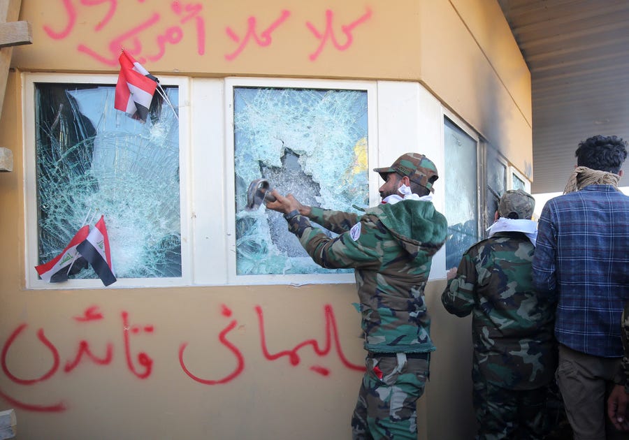 Members the Hashed al-Shaabi, a mostly Shiite network of local armed groups trained and armed by powerful neighbour Iran, smash the bullet-proof glass of the US embassy's windows in Baghdad after breaching the outer wall of the diplomatic mission.