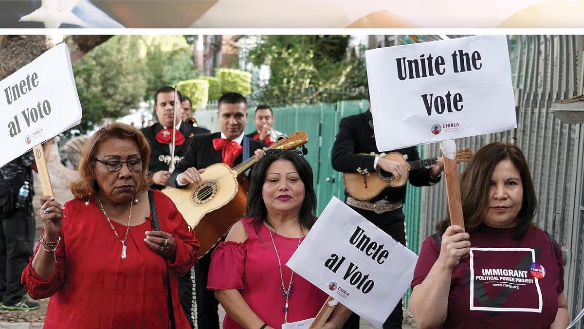 Latino voters carry signs that read "Unite the Vote" as they are serenaded by mariachis on their way to their polling station to cast their ballots in the 2018 midterm general election in Los Angeles, California, Nov. 6, 2018.