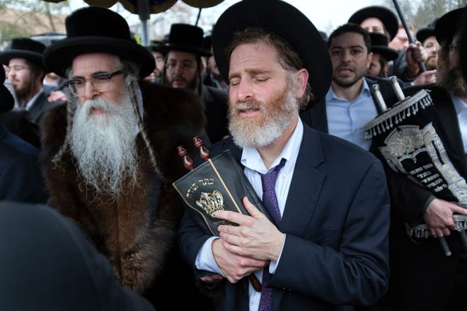 Community members, including Rabbi Chaim Rottenberg, left, celebrate the arrival of a new Torah on Dec. 29, 2019, near the rabbi's residence in Monsey, N.Y. A day earlier, a knife-wielding man stormed into the home and stabbed multiple people as they celebrated Hanukkah in the Orthodox Jewish community.