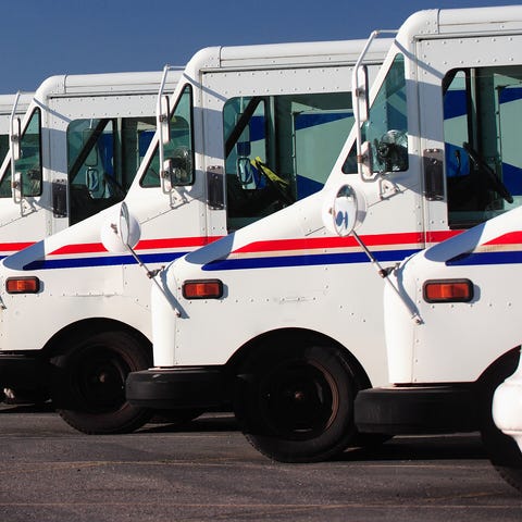 A fleet of US postal service vehicles parked in a 