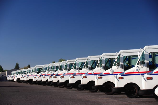 A fleet of US postal service vehicles parked in a line.