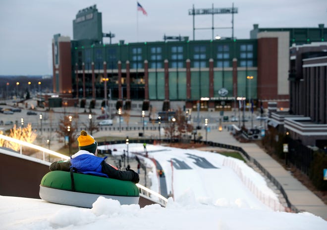 A snow tuber gets a view of Lambeau Field as he begins the ride down Ariens Hill in the Titletown District.