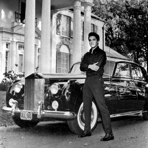 Elvis Presley poses in front of his home with his 
