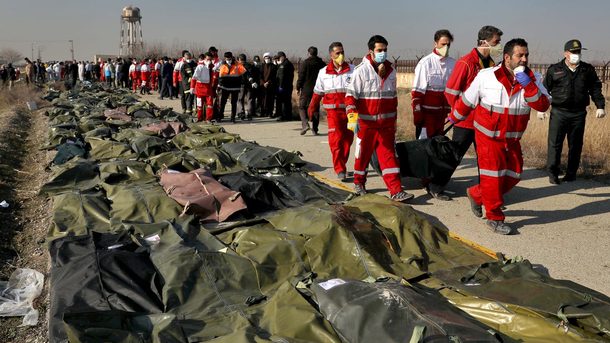 Rescue workers carry the body of a victim of a Ukrainian plane crash in Shahedshahr, southwest of the capital Tehran, Iran,, Jan. 8, 2020. A Ukrainian passenger jet carrying 176 people crashed on Wednesday, just minutes after taking off from the Iranian capital's main airport, turning farmland on the outskirts of Tehran into fields of flaming debris and killing all on board.