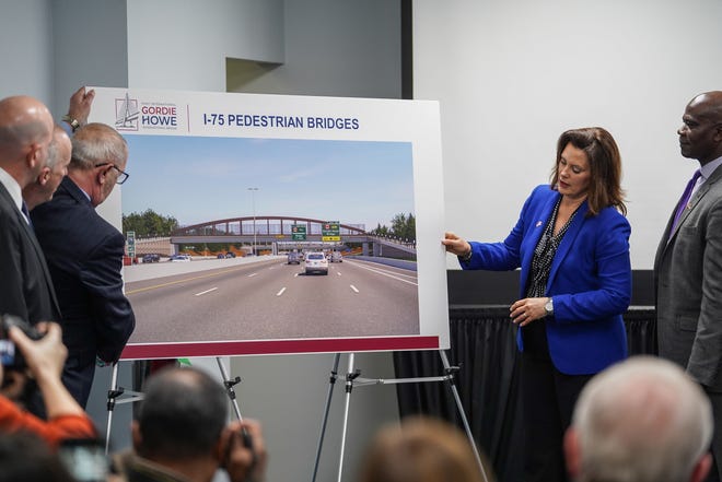 Michigan Governor Gretchen Whitmer helps turn a board with a design illustration for five pedestrian bridges over I-75 as part of the Gordie Howe International Bridge on Thursday, January 09, 2020 during a news conference in southwest Detroit.