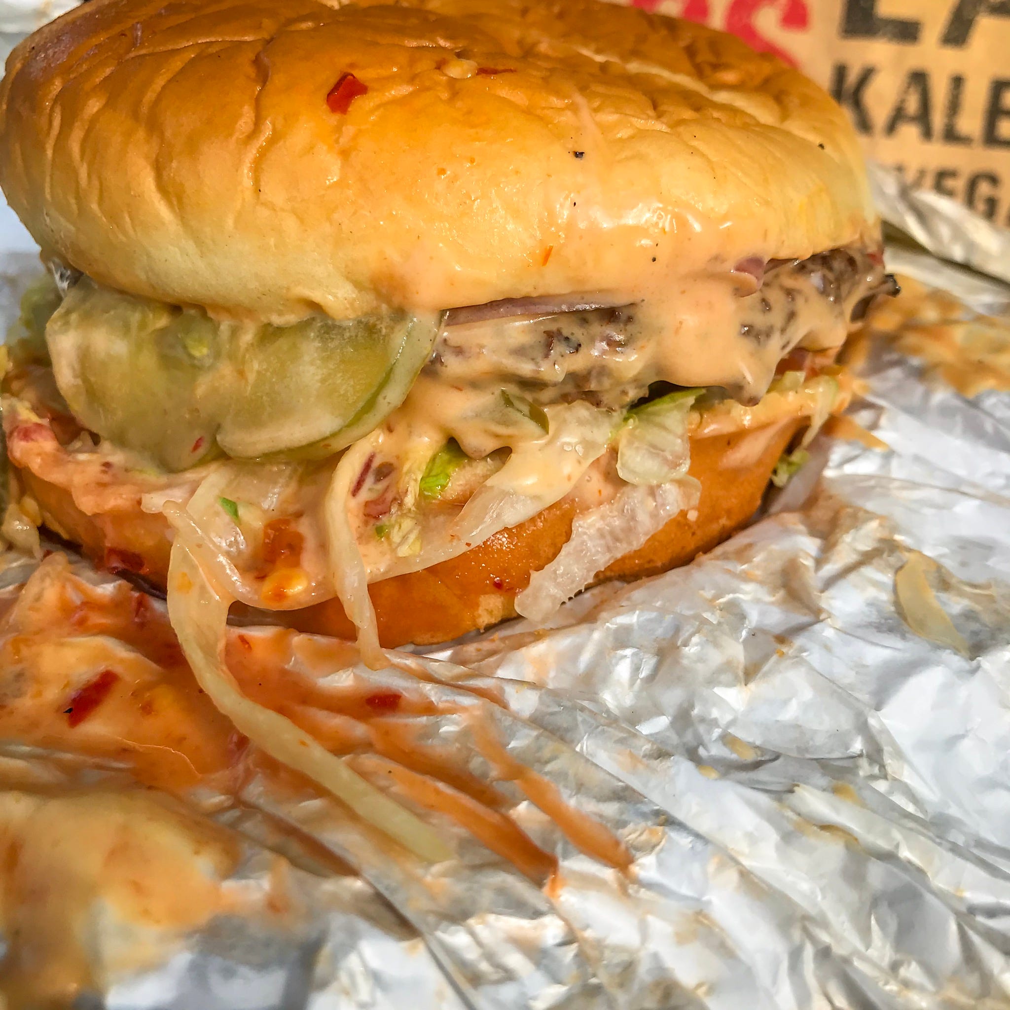 The Fussy Hussy burger fro Atlanta's Slutty Vegan is an non-meat patty topped with pickles, vegan cheese, caramelized onions, lettuce and tomatoes on a Hawaiian bun.