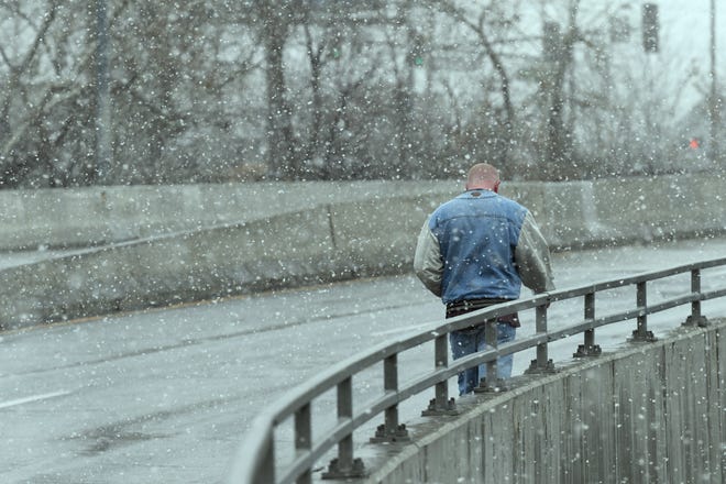 A man walks across the Sutro Street bridge on Jan. 9, 2020 as snow falls on Reno. 