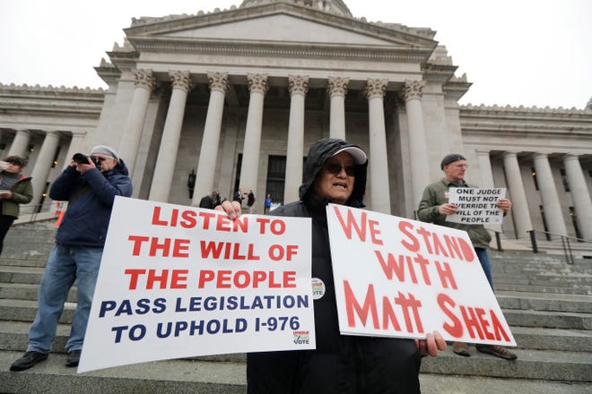 Ed Yasukawa, of Seattle, holds a sign that reads "We Stand With Matt Shea," as he attends a rally, Monday, Jan. 13, 2020, on the first day of the 2020 session of the Washington legislature at the Capitol in Olympia, Wash. The embattled Rep. Matt Shea, R-Spokane Valley, returned to the Capitol Monday amid calls for his resignation following in the wake of a December report that found he was involved in anti-government activities.