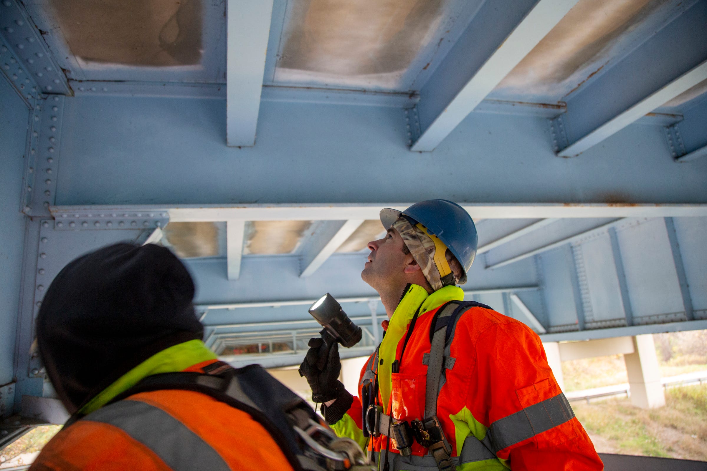 MDOT bridge inspection engineer Andrew Bouvy, right, and MDOT reachall worker Mike Mallory, left, during the fracture critical inspection of the eastbound I-96 bridge over the Grand River and Market Street, near Portland, Michigan, on Oct. 29, 2019. The 60-year-old bridge is in fair condition.