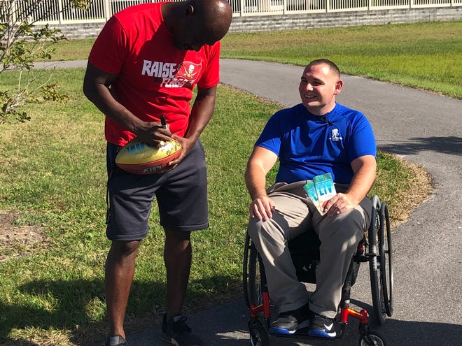 Former Tampa Bay Buccaneers Super Bowl MVP Dexter Jackson of Quincy autographs a football for injured veteran and wounded warrior Mike Delancey Monday afternoon in Pinellas Park, Florida.