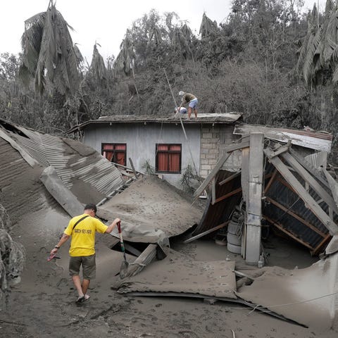 A resident passes a house destroyed by volcanic as